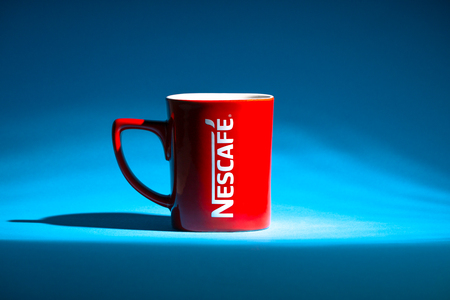 Kuala Lumpur, Malaysia - July 03, 2019:  Promotional red Nescafe mug on blue background. Selective focusのeditorial素材
