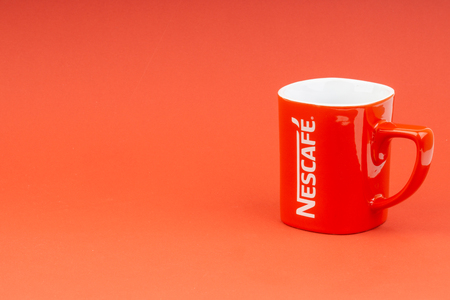 Kuala Lumpur, Malaysia - June 24, 2019: Red Nescafe mug isolate on red background. Selective focusのeditorial素材