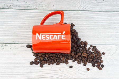 Kuala Lumpur, Malaysia - July 03, 2019: Promotional red Nescafe mug on wooden background. Selective focusのeditorial素材