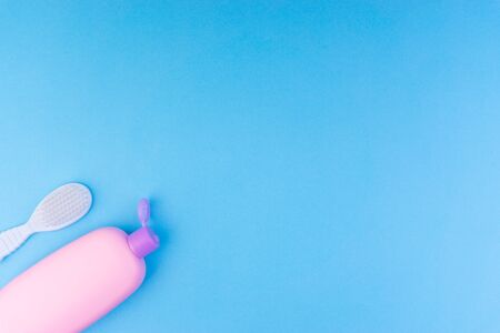 Flat lay composition of baby care products on a blue background. View from above shampoo or shower bottle gel and cleaning brushの写真素材