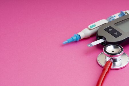 Diabetes concept. Syringe, Glucometer or Glucose meter and stethoscope on pink background. Healthcare and Medicalの写真素材
