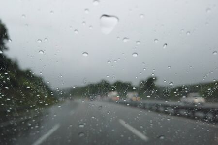 Rain drop falling on car windshield, drive car on street in city in heavy rain