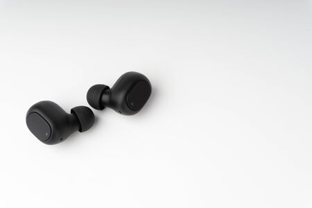 Wireless earbuds or earphones on white background. Copy space and technology concept