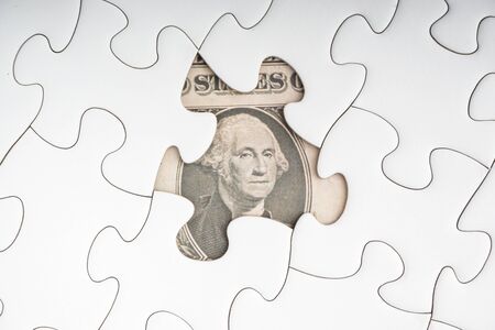 US Dollar banknotes on white jigsaw puzzle. Business and copy space concept