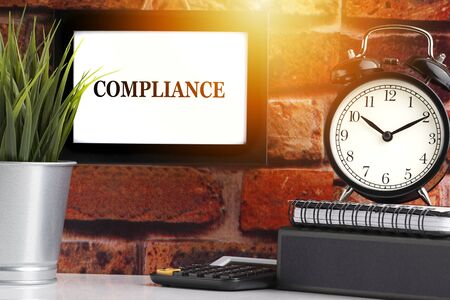 COMPLIANCE text with alarm clock, books and vase on brick background. Business, Quotes and Copy Space conceptの写真素材