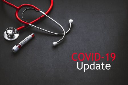 COVID 19 UPDATE text with stethoscope and blood sample vacuum tube on black background. Covid or Coronavirus Conceptの写真素材
