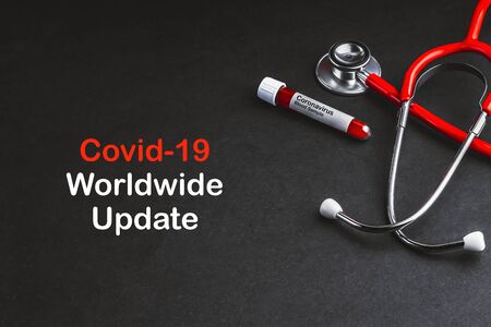 COVID-19 WORLDWIDE UPDATE  text with stethoscope and blood sample vacuum tube on black background. Covid or Coronavirus Conceptの写真素材