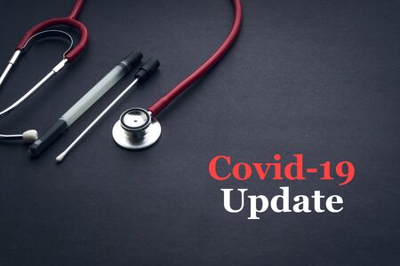 COVID-19 or CORONAVIRUS UPDATE text with stethoscope and medical swab on black background. Covid-19...