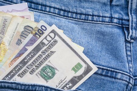 Multi currency banknotes in back pocket of blue jeans. Business concept