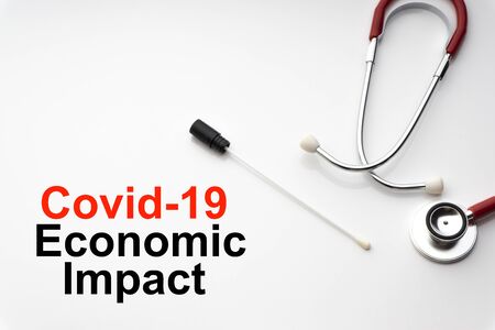 COVID-19 ECONOMIC IMPACT text with stethoscope and medical swab on white background. Covid or Coronavirus Conceptの写真素材