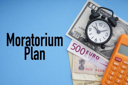 MORATORIUM PLAN text with alarm clock, banknotes currencies and calculator on blue background. Coronavirus Covid19 and Business Conceptの写真素材