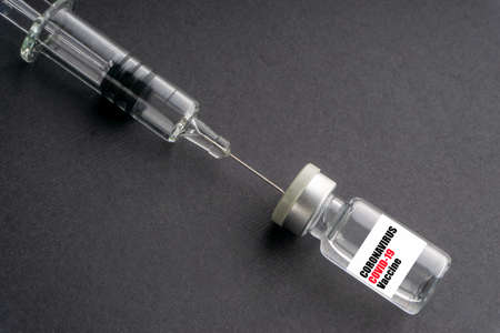 CORONAVIRUS COVID-19 VACCINE text with syringe and vials on black background. Covid-19 and Coronavirus conceptの写真素材