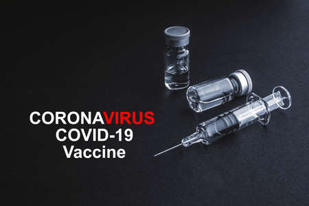 CORONAVIRUS COVID-19 VACCINE text with syringe and vials on black background. Covid-19 and Coronavirus conceptの写真素材