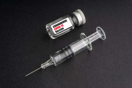 CORONAVIRUS COVID-19 VACCINE text with syringe and vials on black background. Covid-19 and Coronavirus conceptの写真素材