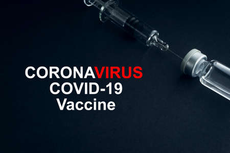 CORONAVIRUS COVID-19 VACCINE text with syringe and vials on black background. Covid-19 and...