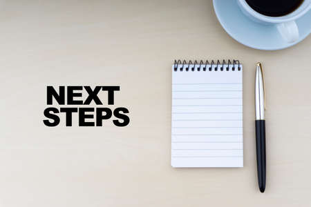 NEXT STEPS text with fountain pen and cup of coffee on wooden background.Business and copy space concept.の写真素材