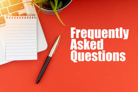 FREQUENTLY ASK QUESTIONS or FAQ text with notepad, laptop, fountain pen and decorative plant on red background. Business and Copy Space Conceptの写真素材