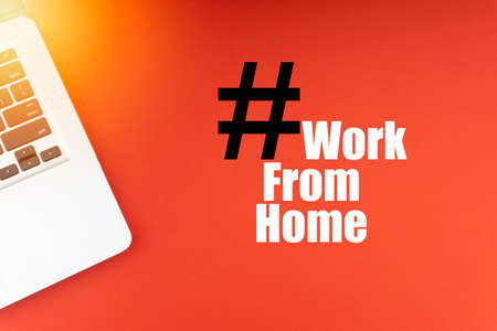 WORK FROM HOME text with laptop on red background. Business and Copy Space Conceptの写真素材