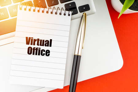 VIRTUAL OFFICE text with notepad, laptop, fountain pen and decorative plant on red background. Business and Copy Space Conceptの写真素材
