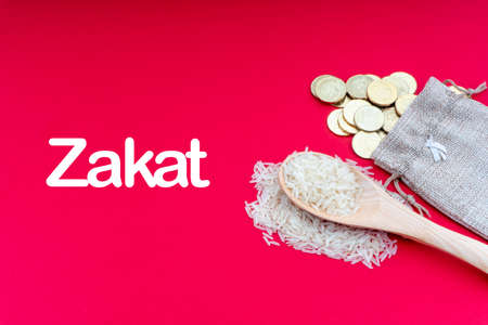 ZAKAT words with Coins and Rice on red background. Zakat concept. Zakat is a form of alm-giving as a religious obligationの写真素材