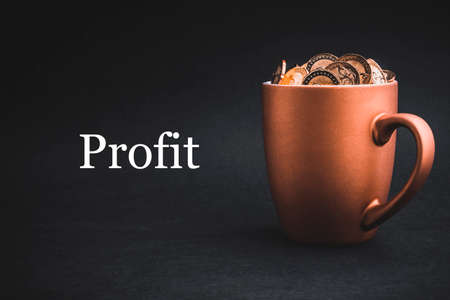 PROFIT text with Coins in cups on black background. Tax, Savings, Profit and Investment Conceptの写真素材