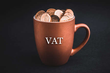 VAT text with Coins in cups on black background. Tax, Savings, Profit and Investment Conceptの写真素材