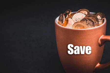 SAVE text with Coins in cups on black background. Tax, Savings, Profit and Investment Conceptの写真素材