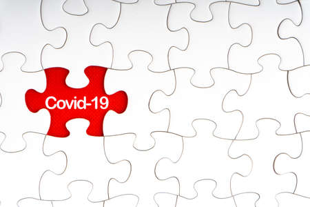 COVID-19 text with jigsaw puzzle on red background. Covid-19 and Coronavirus Conceptの写真素材