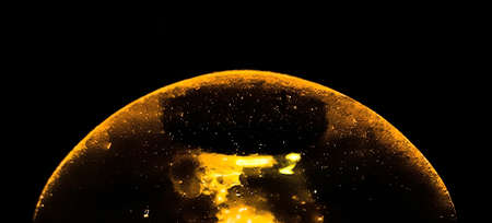 In the darkness of the night the table lamps are burning inside the room, the glass color are black...