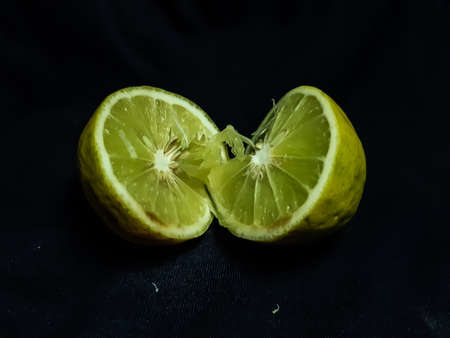 Cut in the middle of a lemon on a black background. Lemon contains lemon seeds and juice.の写真素材