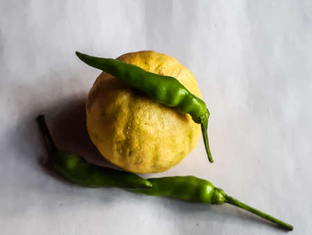 Yellow ripe lemons and raw peppers are on a white background. Lemons contain citric acid, raw peppers contain vitamin C which is beneficial for the human body.の写真素材