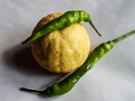 Yellow ripe lemons and raw peppers are on a white background. Lemons contain citric acid, raw peppers contain vitamin C which is beneficial for the human body.の写真素材