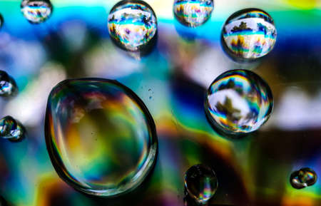 Drops of rain water are falling on CD dix and reflecting sunlight. Yellow blue and red light is being reflected.の写真素材
