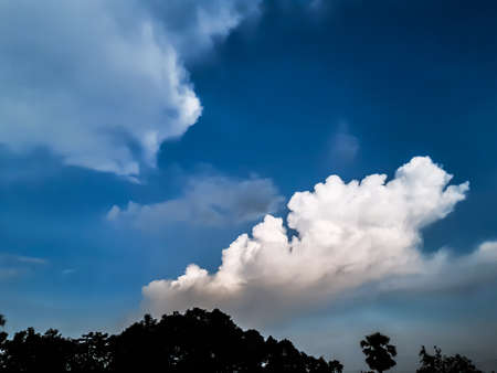 At sunset, farmland in Indian villages and black clouds in the blue sky, through which the light of...
