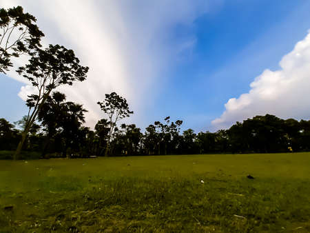 At sunset, farmland in Indian villages and black clouds in the blue sky, through which the light of the sun is shining.の写真素材