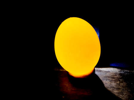 The light is on behind an egg and the egg has a bright shape, black background. This is a picture of the darkness of night.の写真素材