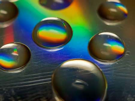 Water drops CD discs reflecting light. This light is blue, yellow and green.の写真素材