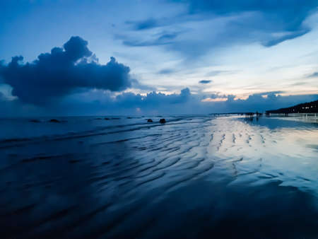 The beauty of India's long sea at sunset. Black clouds in the blue sky and the reflection of red sunlight.の写真素材