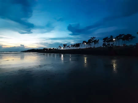 The beauty of India's long sea at sunset. Black clouds in the blue sky and the reflection of red sunlight.の写真素材