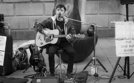 Cambridge, United Kingdom - April 17, 2016: A teenage boy playing multiple instruments and singing...