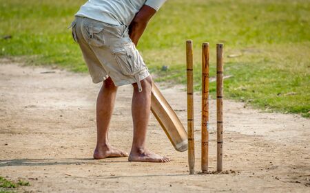 A young Indian boy playing cricket. View of a right handed batsman with all three stumps visible.の写真素材