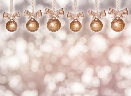 hanging golden christmas balls with ribbon in front of unsharp backgroundの写真素材