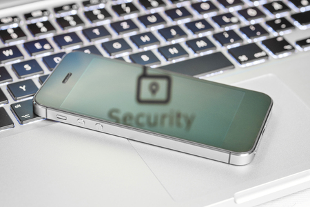 smartphone on top of keyboard of laptop with security signの写真素材