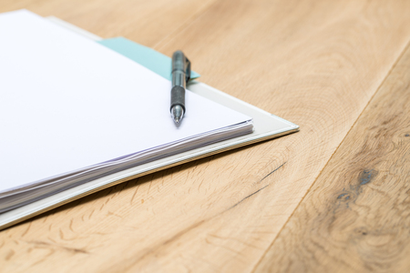 Blank notepad with pen lying on wooden table as closeupの写真素材