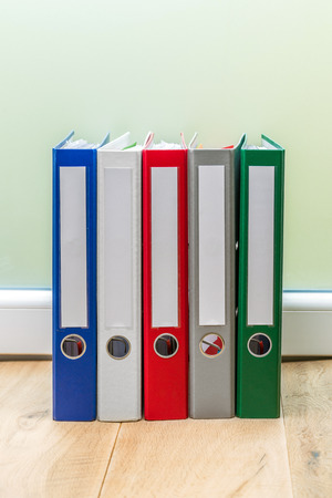 Group of colourful folders in a row on wooden tableの写真素材