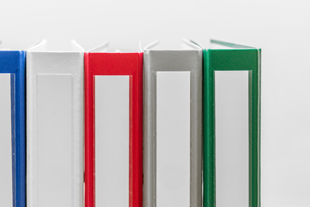 Closeup of group of colourful folders in a row on the left side of white backgroundの写真素材