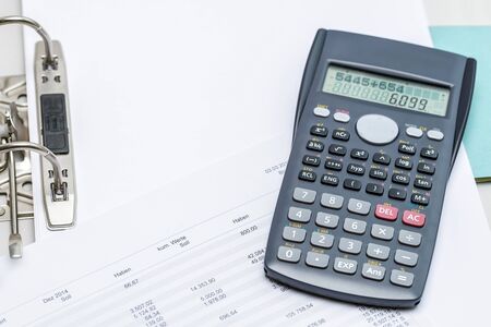 Charts with calculator lying on top of opened folderの写真素材