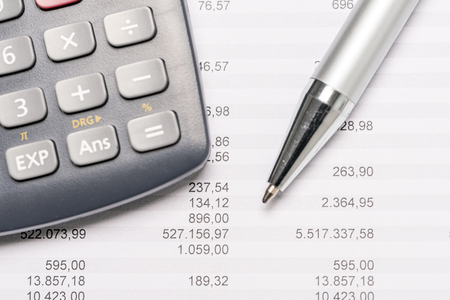 Calculator lying on top of sheet of paper with charts as closeup