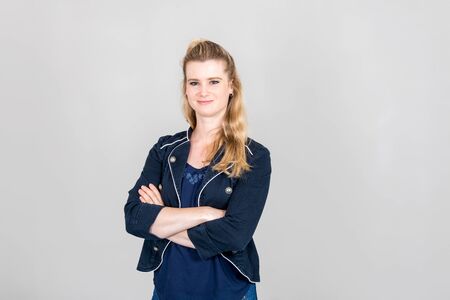 Studio shot of confident smiling woman with folded arms looking into the camera in front of white backgroundの写真素材