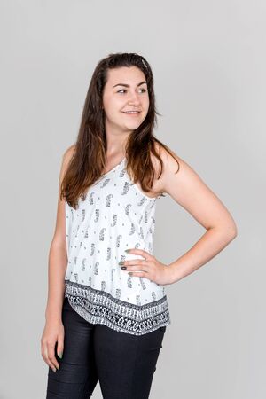 Studio shot of open beautiful smiling girl with left hand on hipの写真素材